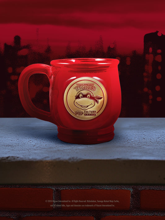 The handthrown stoneware mug for the Teenage Mutant Ninja Turtle, Raphael, featuring a bold red glaze.